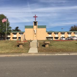A church building featuring a cross and an American flag in the foreground.