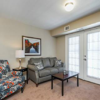 A cozy living room with a gray sofa, colorful armchair, and coffee table near French doors.