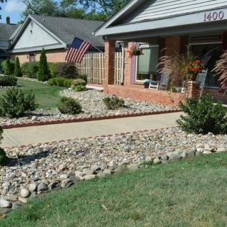 A suburban house with a landscaped front yard featuring a stone pathway and an American flag.