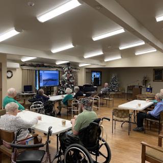 Residents of a nursing home enjoy a community activity in a decorated room.