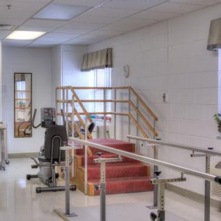 A physical therapy room equipped with parallel bars and exercise equipment.