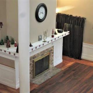 A cozy living room with a decorated fireplace and a wall clock.