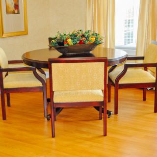 A cozy dining area featuring a round wooden table with four chairs and a decorative fruit bowl centerpiece.