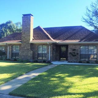 A suburban brick house with a well-maintained lawn and chimney.