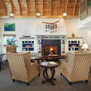 A cozy living room with a fireplace, comfortable seating, and a wooden ceiling.