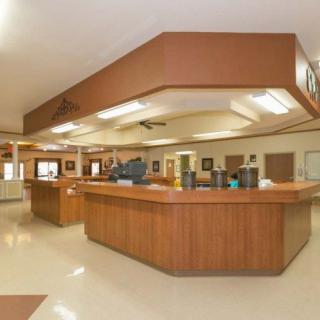 A spacious reception area featuring a large wooden counter under bright ceiling lights.