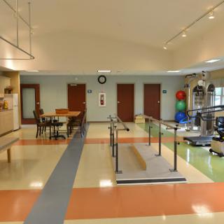 A spacious physical therapy room equipped with various rehabilitation tools and an accessible walking path.