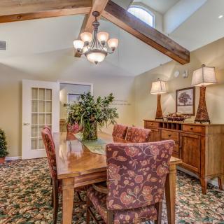 A cozy dining room with a wooden table, floral patterned chairs, and decorative lighting.