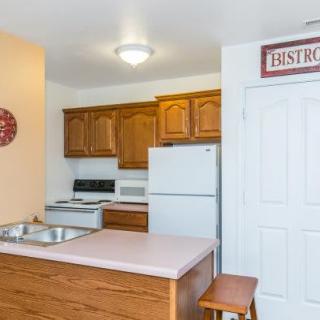 A cozy kitchen interior with wooden cabinets, a fridge, oven, and a sink.