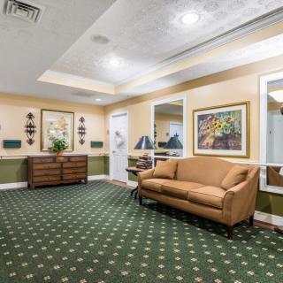 A warmly lit lobby with a sofa, artwork, and carpeted flooring.