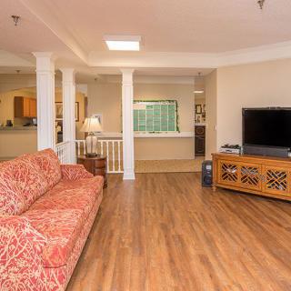A cozy living room with a wooden floor, featuring a patterned sofa and a television on a stand.
