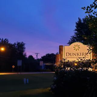 A tranquil evening view featuring the Dunkirk sign against a colorful sunset.