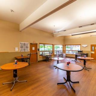 An empty dining room with round tables and wooden flooring.
