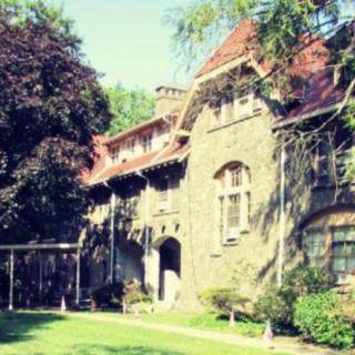 A charming historic building surrounded by lush greenery on a bright, sunny day.