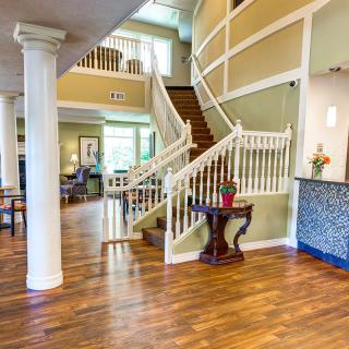 Spacious lobby with a grand staircase and wooden flooring.