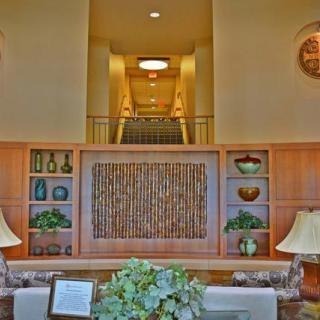 A hotel lobby with elegant interior design, featuring decorative shelves, plants, and a staircase leading upwards.