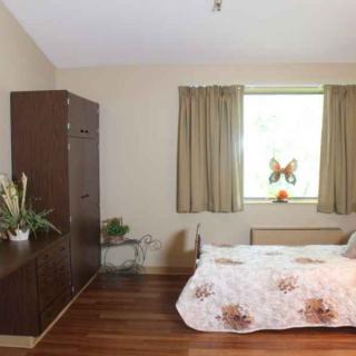 A cozy bedroom with a bed, wardrobe, and a window adorned with curtains.