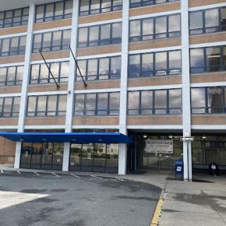 A modern multi-story building featuring large windows and a covered entrance.