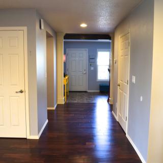 A view of a residential hallway with wooden flooring and light gray walls.
