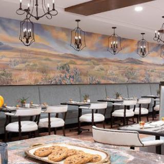 A beautifully designed dining area featuring elegant lighting, a stunning mural, and a tempting display of cookies.