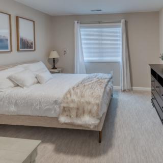 A modern and minimalist bedroom featuring a neatly made bed, light color scheme, and simple decor.