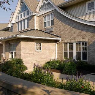 A beautiful residential house with brick exterior and lush garden landscaping.