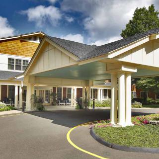 A covered entrance to a large building with columns and a circular driveway.