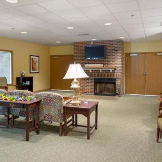 A cozy lounge area featuring a brick fireplace, comfortable seating, and a television.