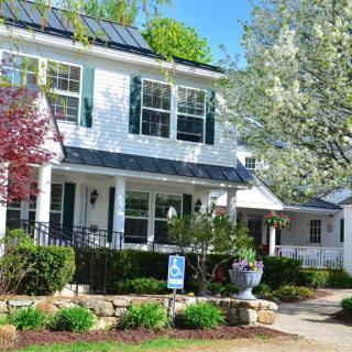 A charming two-story house with solar panels and a well-maintained garden.