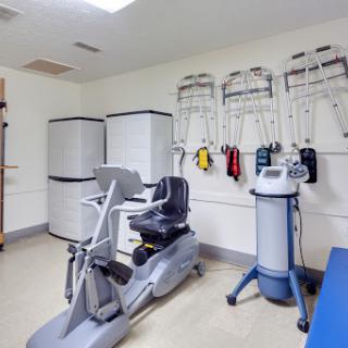 A well-equipped exercise room featuring a recumbent bike and rehabilitation tools.