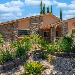 A single-story house with a stone facade and desert landscaping under a sunny sky.