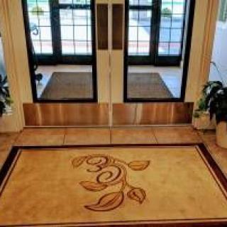 A welcoming entrance with a decorative doormat and glass doors.