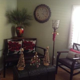 A cozy living room decorated with holiday ornaments, featuring a clock, a vase with a plant, and comfortable seating.