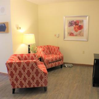 A cozy living room with patterned armchairs and a floor lamp.