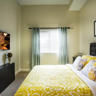 A cozy bedroom with bright yellow bedding and a wall-mounted TV.