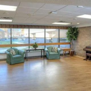 A spacious waiting area with large windows, natural light, comfortable chairs, and a piano.