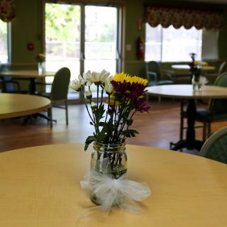 A lovely arrangement of flowers in a vase placed on a table in a bright indoor dining area.