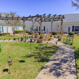 A serene garden with a pergola and pathway, surrounded by a well-maintained lawn.