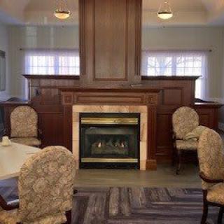 A cozy dining area with a central fireplace surrounded by upholstered chairs.