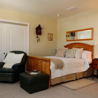 A cozy bedroom with a wooden bed, armchair, and decorative elements.