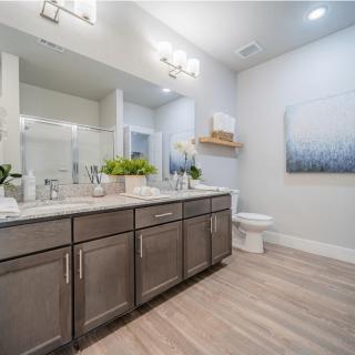 A modern bathroom featuring a double vanity, large mirror, and minimalistic decor.