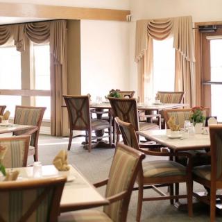 An elegantly decorated dining room with neatly arranged tables and chairs, bathed in natural light.