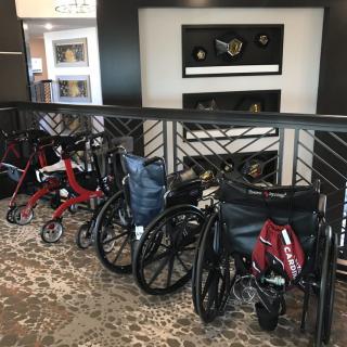 A row of wheelchairs and mobility aids lined up indoors.