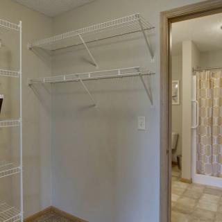 An empty walk-in closet with wire shelving and a view into an adjoining bathroom.