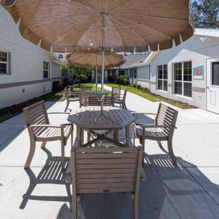 A sunny outdoor patio area with a table, chairs, and an umbrella.