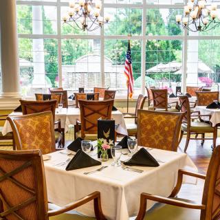 An elegant dining area with neatly arranged tables and chairs, featuring large windows that let in ample natural light.