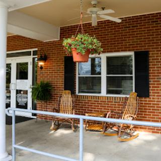 A cozy porch featuring rocking chairs and a hanging plant, perfect for relaxing outdoors.