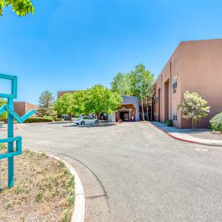 A modern building with a unique sculpture at the entrance, surrounded by trees and a clear blue sky.