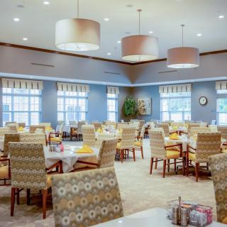 An elegant and spacious dining area with neatly arranged tables and chairs, illuminated by overhead lights.