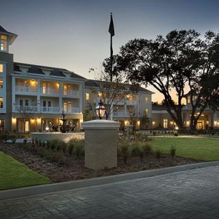 An illuminated hotel building with a landscaped entrance at dusk.